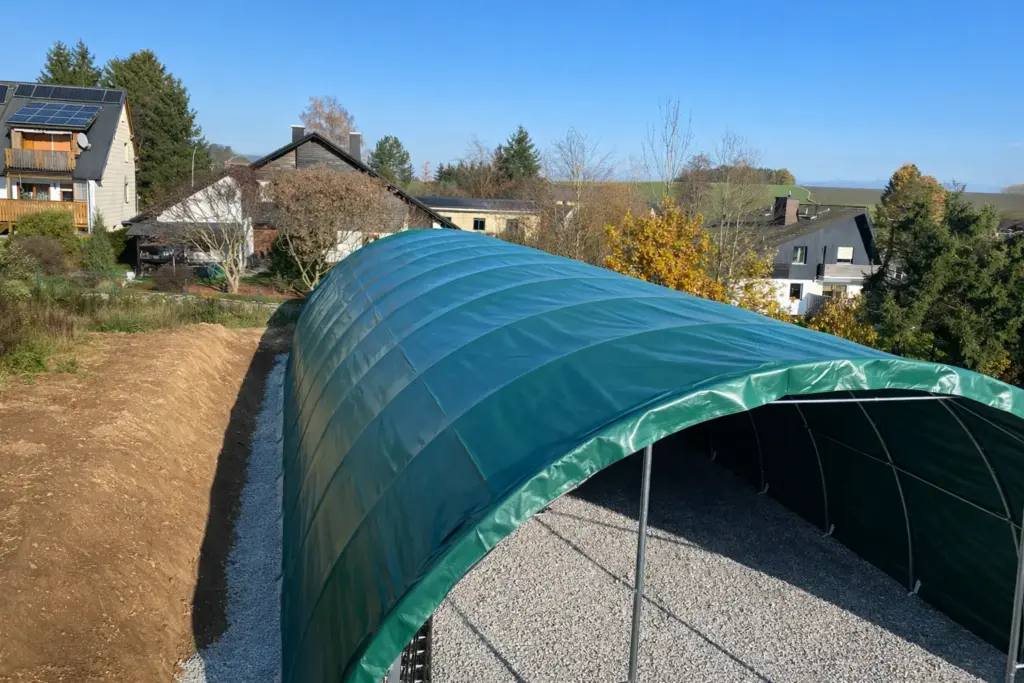 Rundbogenhalle mit PVC-Plane – Außenansicht auf landwirtschaftlicher Fläche